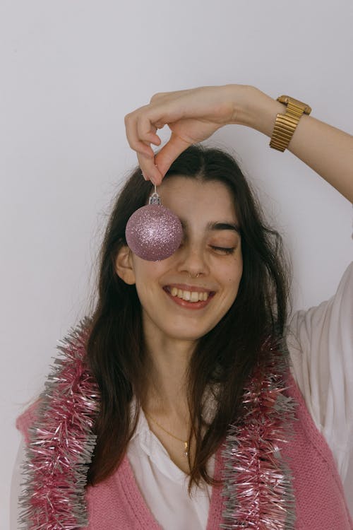 Young Woman Wearing a Tinsel around Her Neck and Holding a Pink Bauble 
