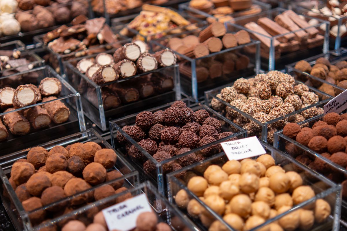 Delicious selection of chocolate truffles in clear containers at a market.