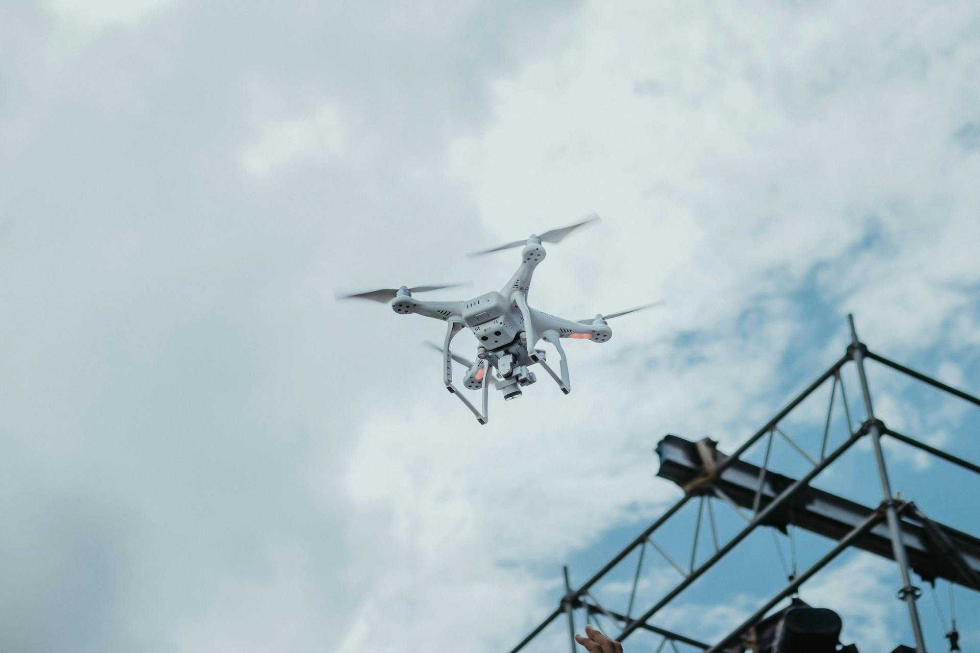 A drone hovering in the sky amidst clouds, showcasing technology in action.