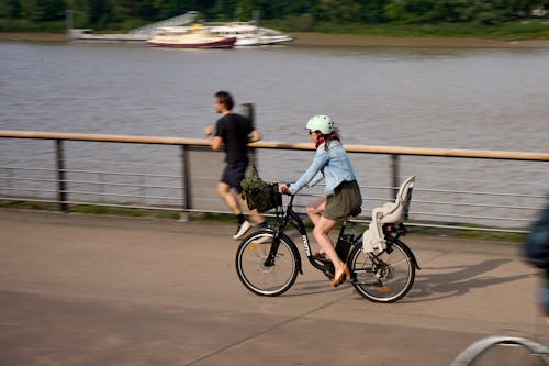 Bordeaux, France, 05.23.2023 Discover the tranquility of cycling along a serene waterfront. Join a woman as she effortlessly pedals.