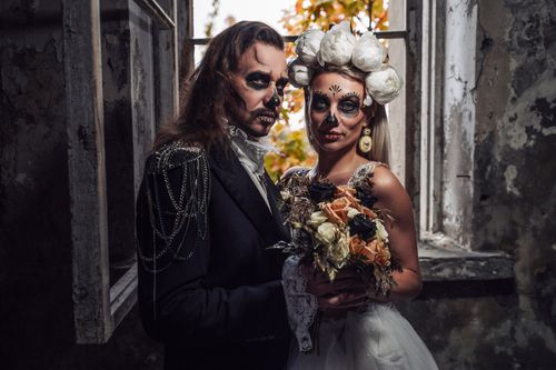 Free A couple dressed in Halloween attire and makeup resembling sugar skulls, in a dramatic setting. Stock Photo
