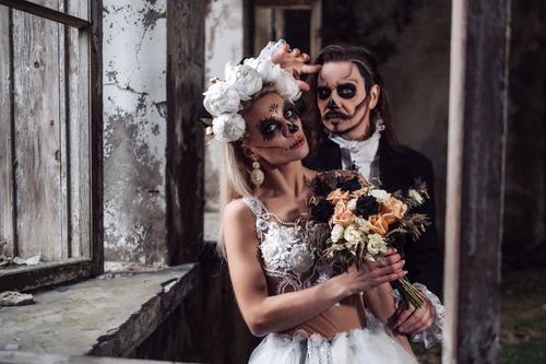 Free A couple in Day of the Dead makeup poses in an abandoned building, creating a spooky wedding scene. Stock Photo