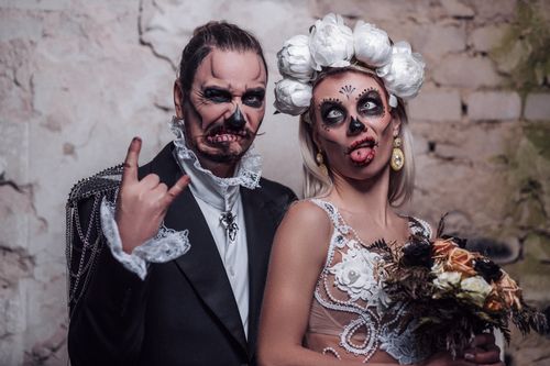 Free Couple dressed in Halloween-themed wedding attire with skeleton makeup, creating a gothic and festive atmosphere. Stock Photo