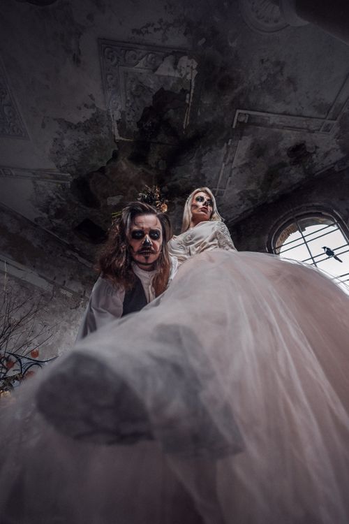Free A gothic couple dressed for Halloween in a haunted setting, creating a dramatic atmosphere. Stock Photo