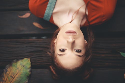 Free Woman Lying on Brown Wooden Surface Stock Photo