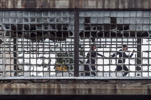 Free A couple runs past shattered glass windows in a dilapidated structure, capturing motion and decay. Stock Photo