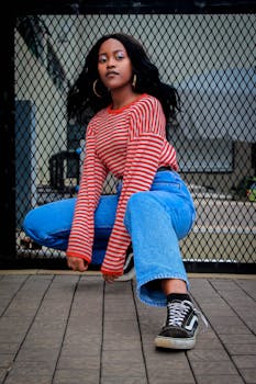 一位穿着休闲装的时尚女士在户外自信地对着金属栅栏摆姿势