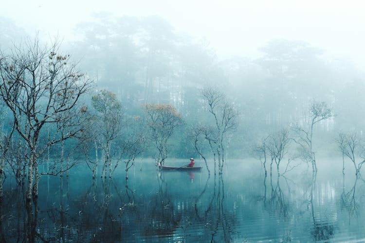 Man In A Traditional Boat Sailing On A Pond In Mist