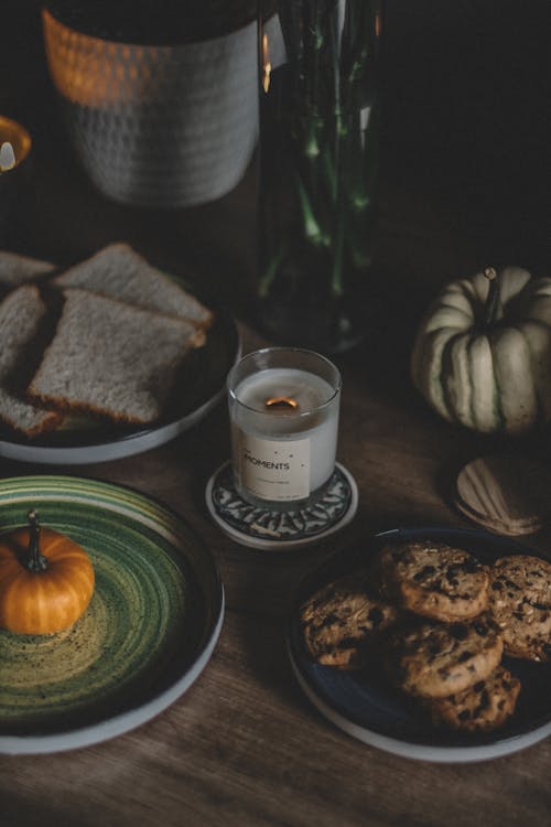 Cookies and Toasts on a Table Decorated with Pumpkins and Scented Candle