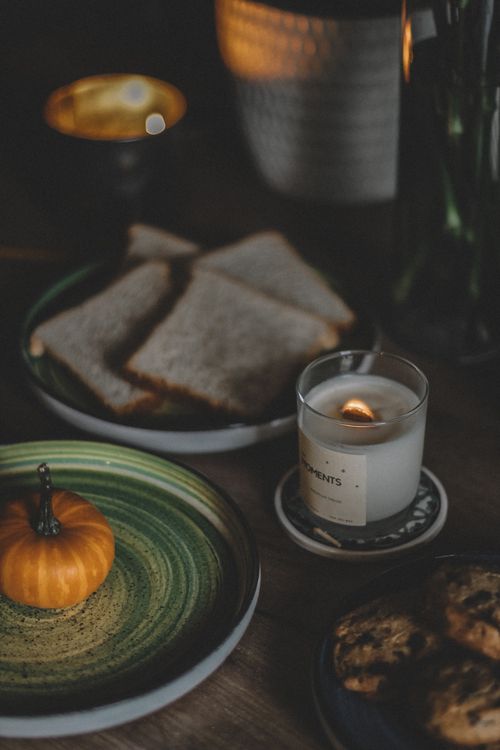 Free Warm autumn scene with bread, candle, plates, and pumpkin for a cozy ambiance. Stock Photo