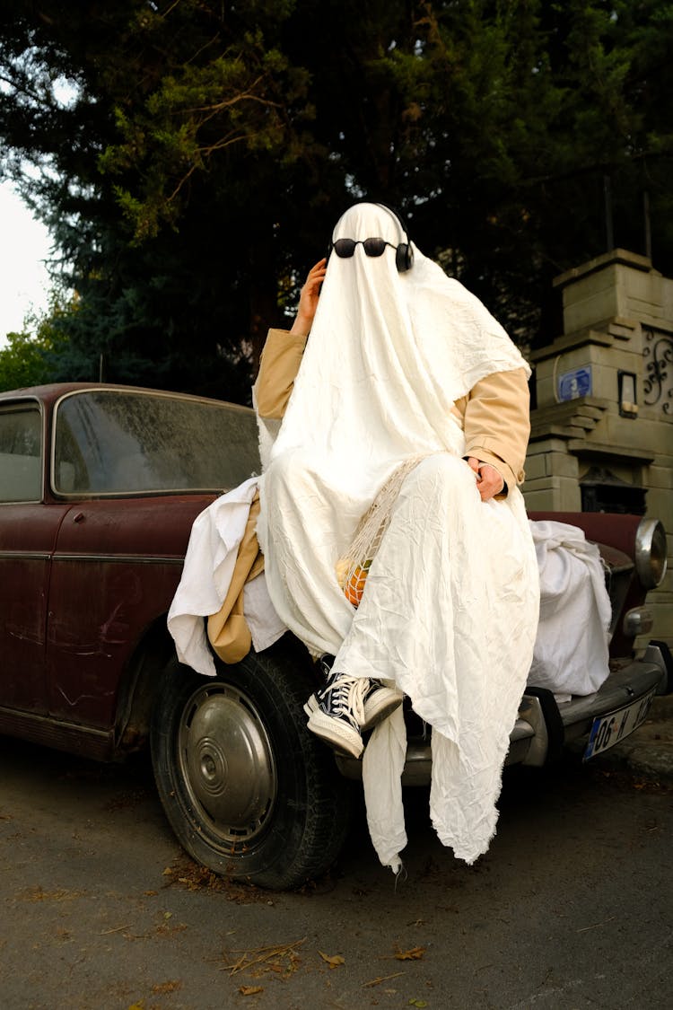 Man Wearing Sheet Sitting On A Car 