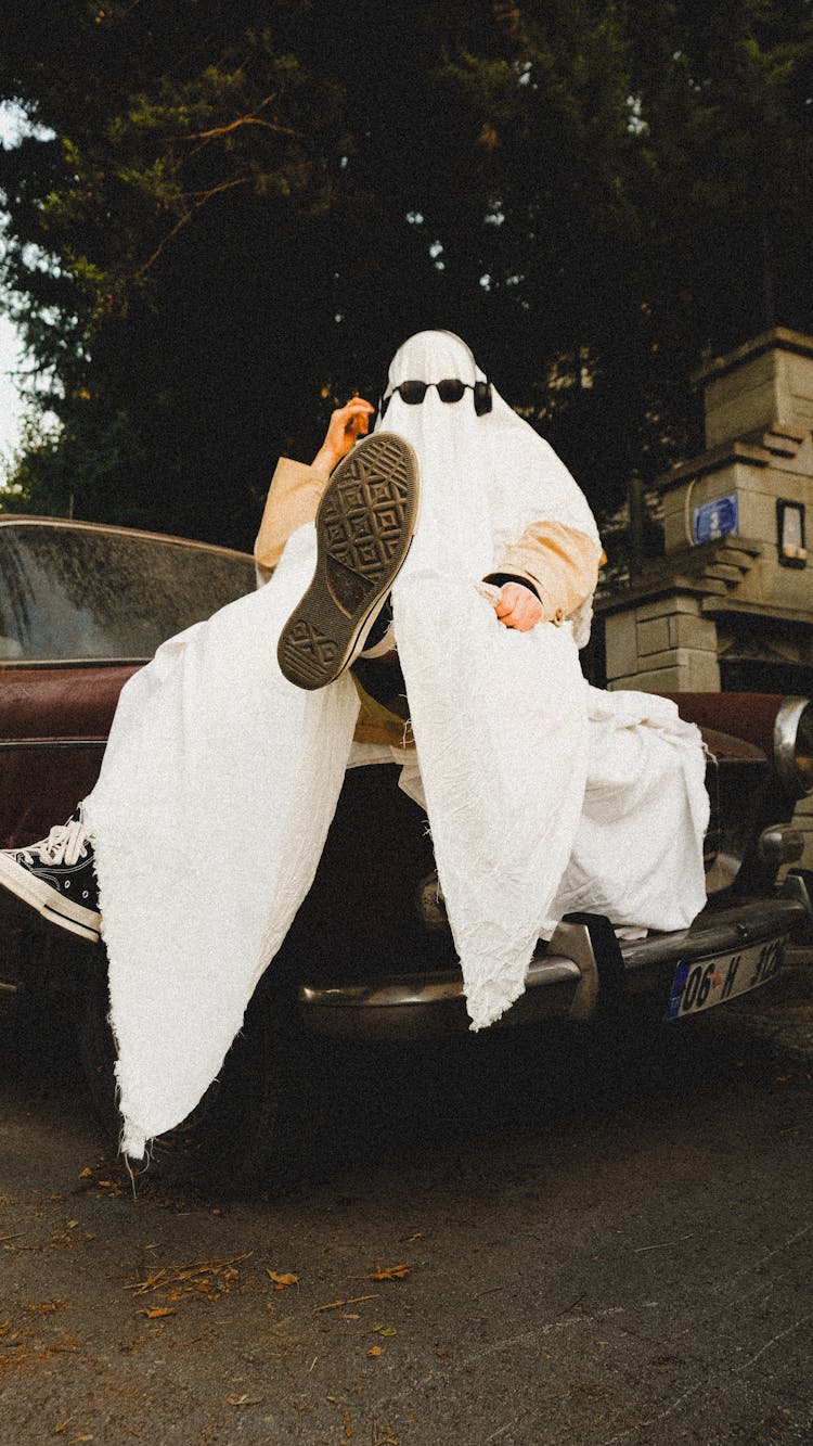 Man Wearing Sheet Sitting On A Car 