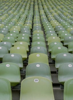 Close-up view of empty green stadium seats with numbered labels, in neat rows.
