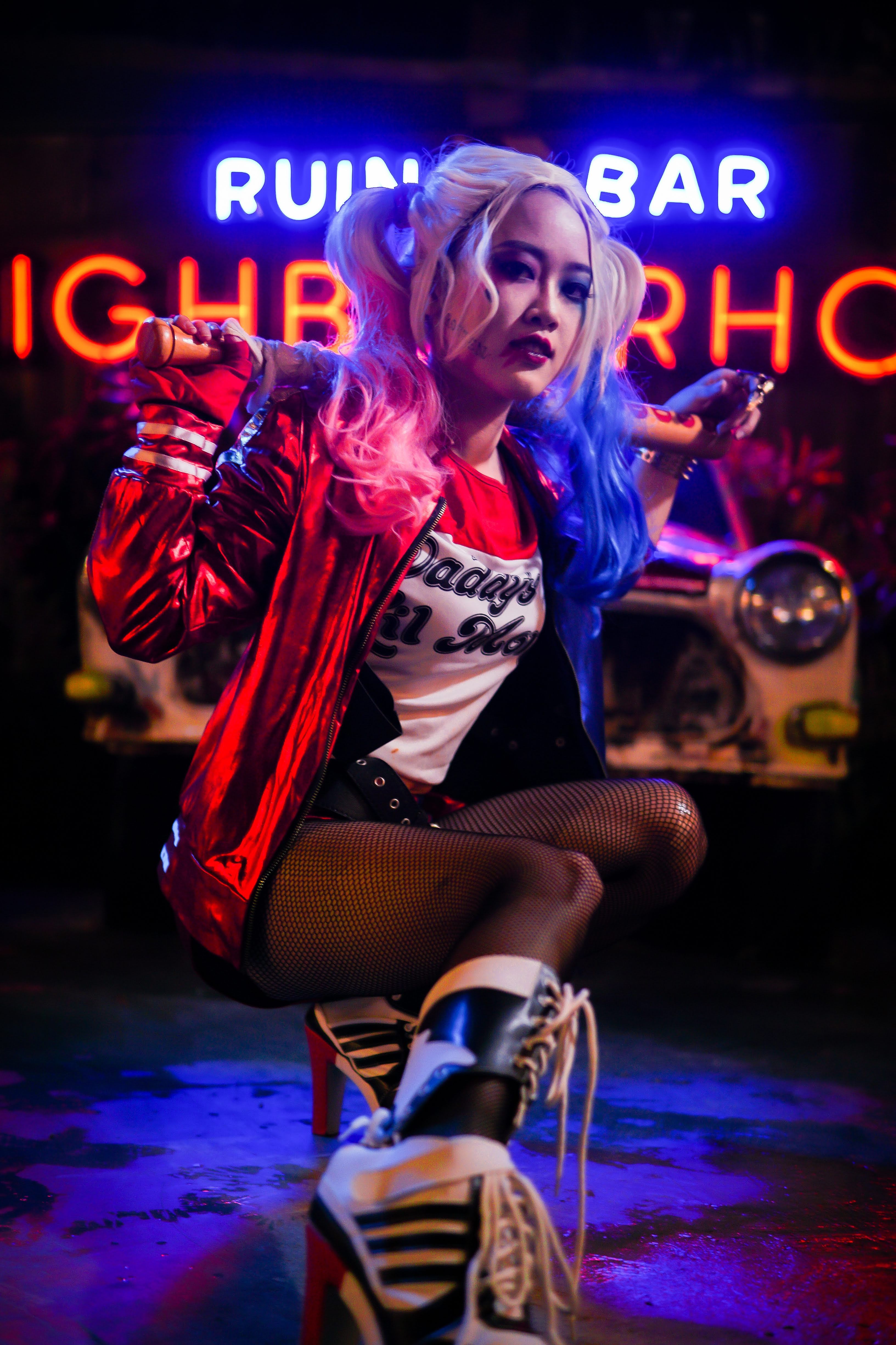 Colorful cosplay character posing under neon lights at a night bar setting.