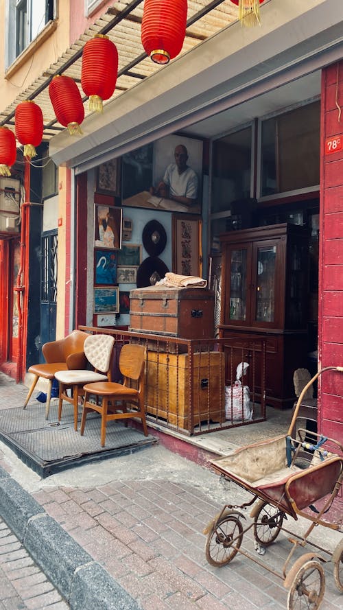 Antique Baby Carriage and Wooden Trunks in Front of an Antique Shop