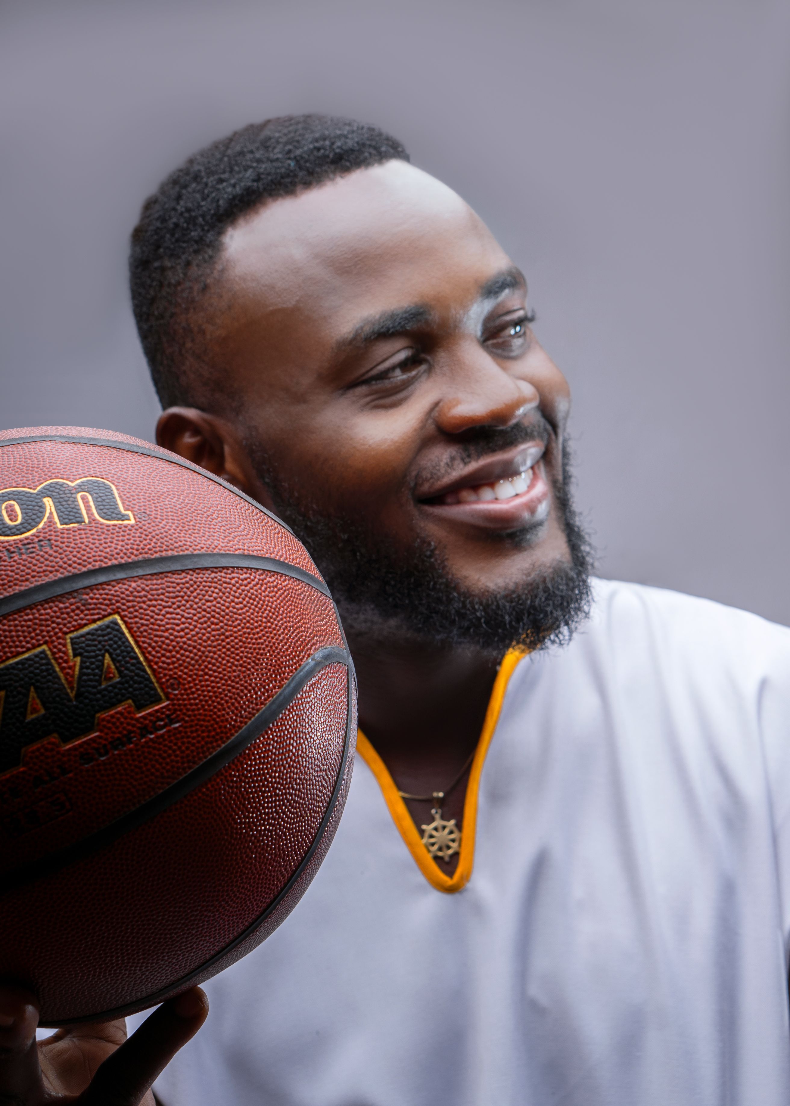A cheerful man with a beard holds a basketball in Tema, Ghana, symbolizing leisure and sports.