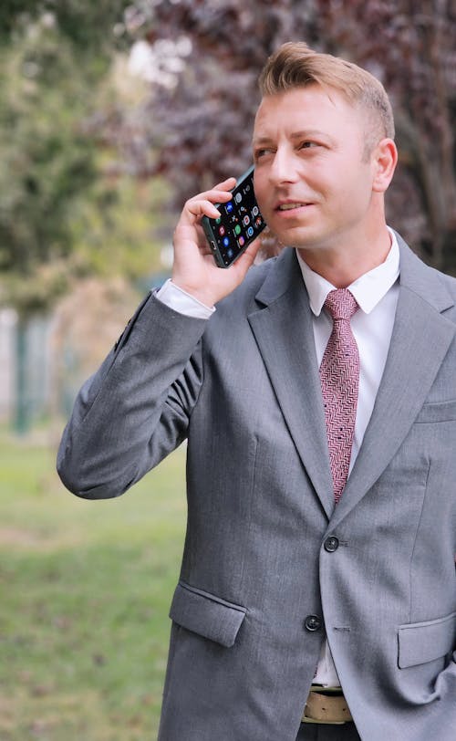 Man in Gray Suit Talking on Phone