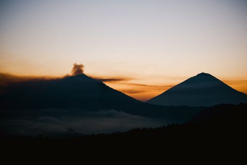 Free Two tranquil mountain peaks silhouetted against a vibrant sunset sky, evoking peace and wonder. Stock Photo