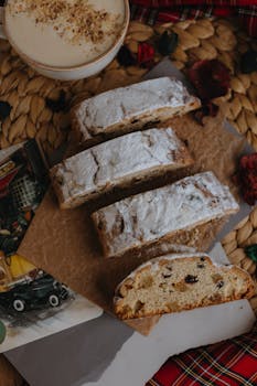 Slices of traditional stollen bread with cappuccino on a rustic table setting, perfect for a cozy holiday ambiance.