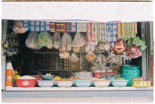 Free Vibrant market stall showcasing spices, grains, and packaged snacks in an Asian bazaar. Stock Photo