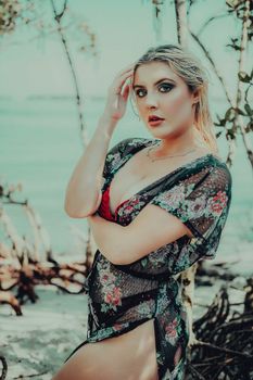 Elegant woman posing in floral dress by seaside during daytime.