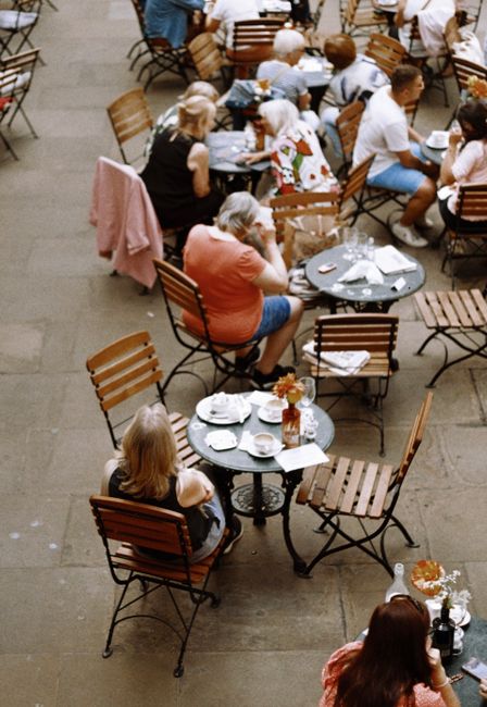 Aerial view of people dining outdoors in a charming London courtyard with wooden tables and chairs.