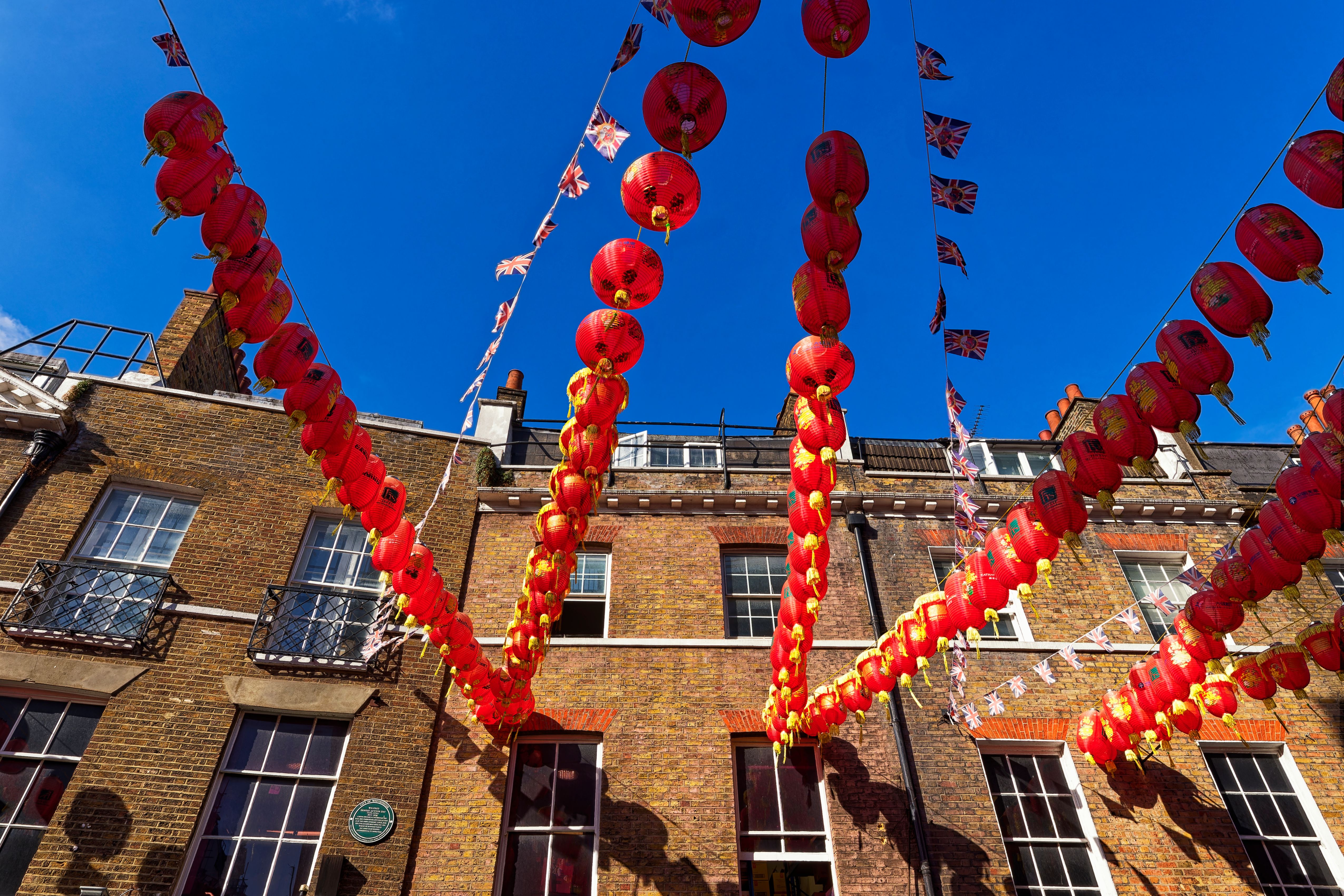 Vibrant red lanterns hanging against a blue sky in London's Chinatown, celebrating culture and tradition.