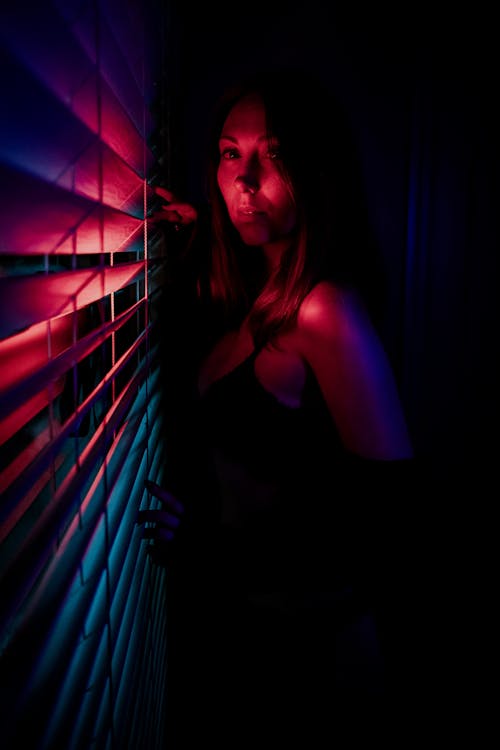 Free Woman by the Roller Blind in Red Light  Stock Photo