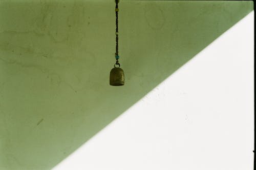 Old Brass Bell Hanging by a Greenish Wall