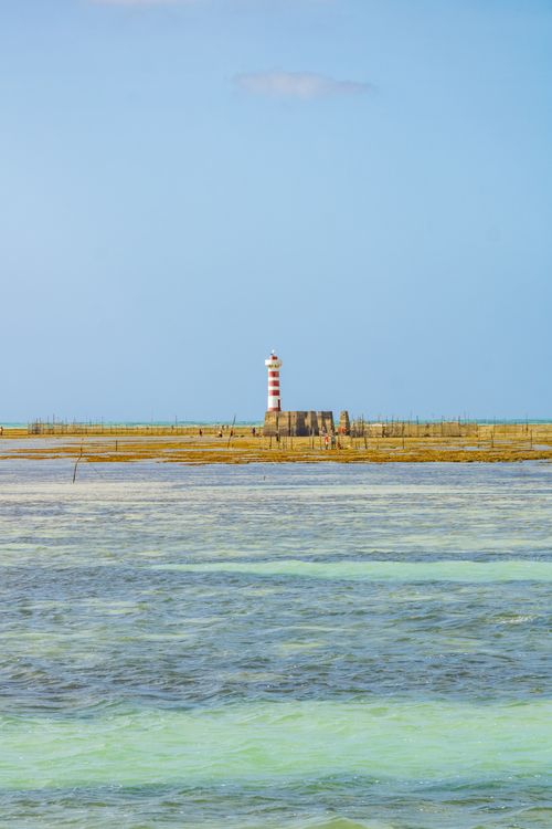 Free Scenic view of a red-striped lighthouse on a peninsula in Maceió, Brazil, against clear blue skies. Stock Photo