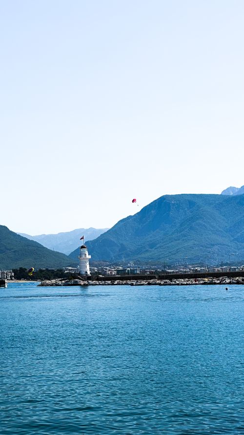 Free Lighthouse in Alanya Bay with mountains and clear blue sea under a bright day sky. Stock Photo