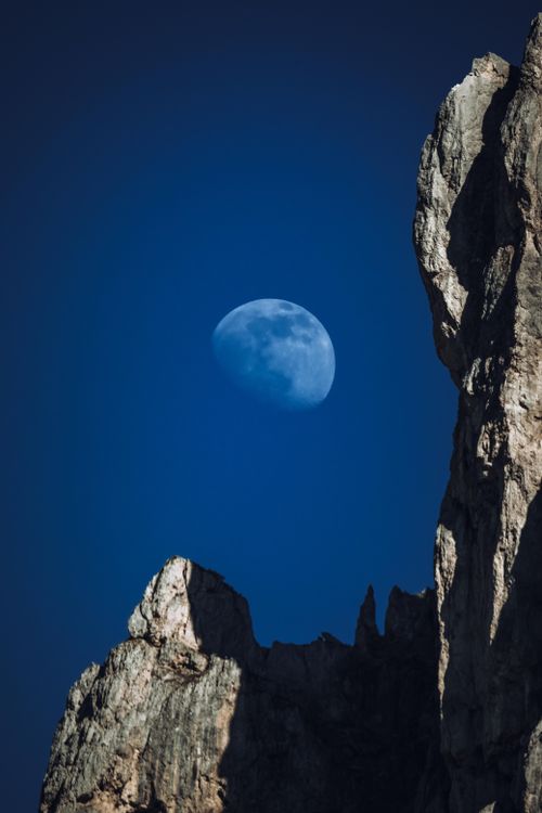 Free A captivating shot of a full moon rising over rugged rocks in the evening sky. Stock Photo
