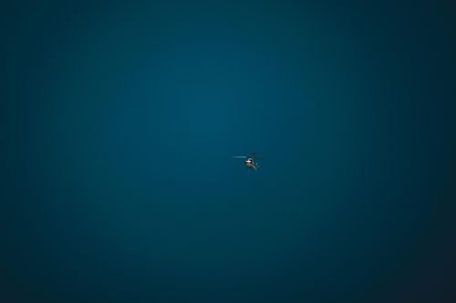Free A small helicopter hovers alone in a vast, clear blue sky, symbolizing freedom and isolation. Stock Photo