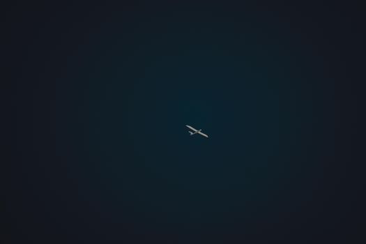 A solitary airplane cuts through the sky in a minimalist aerial shot, invoking a sense of travel and freedom.