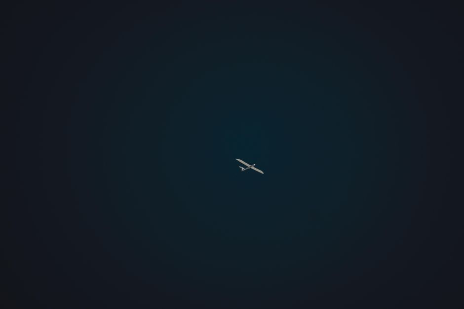 A solitary airplane cuts through the sky in a minimalist aerial shot, invoking a sense of travel and freedom.