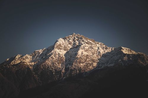 Free A stunning view of a snow-covered mountain peak under a clear sky at dusk. Stock Photo