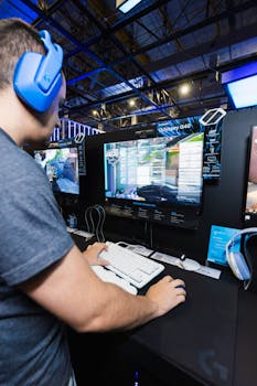 A competitive gamer using a high-performance PC with a headset in a gaming exhibition.
