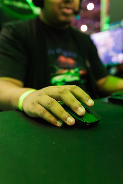 Free A gamer using a wireless mouse at an indoor gaming event, emphasizing technology and leisure. Stock Photo
