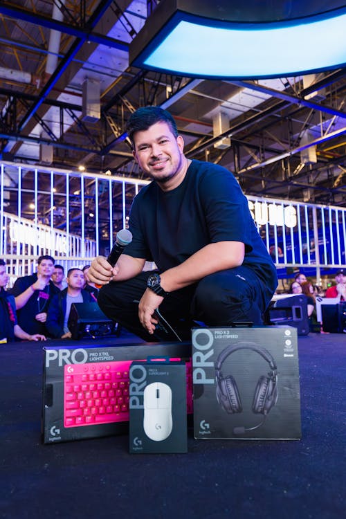 Man with a Microphone Next to Boxes with Logitech Gaming Peripherals at ...