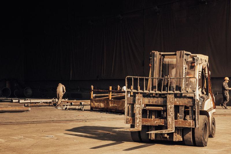 Industrial scene with workers and a forklift inside a warehouse