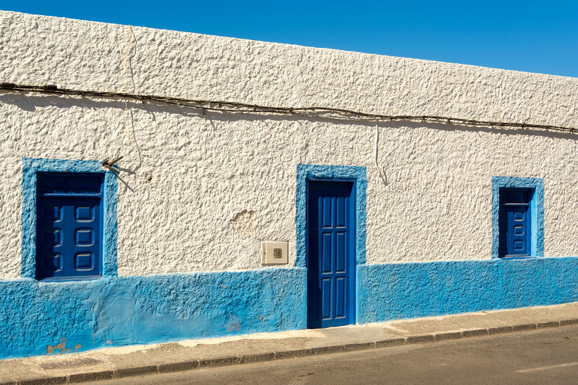 A bright blue and white urban house facade under a clear sky, showcasing classic architectural style.