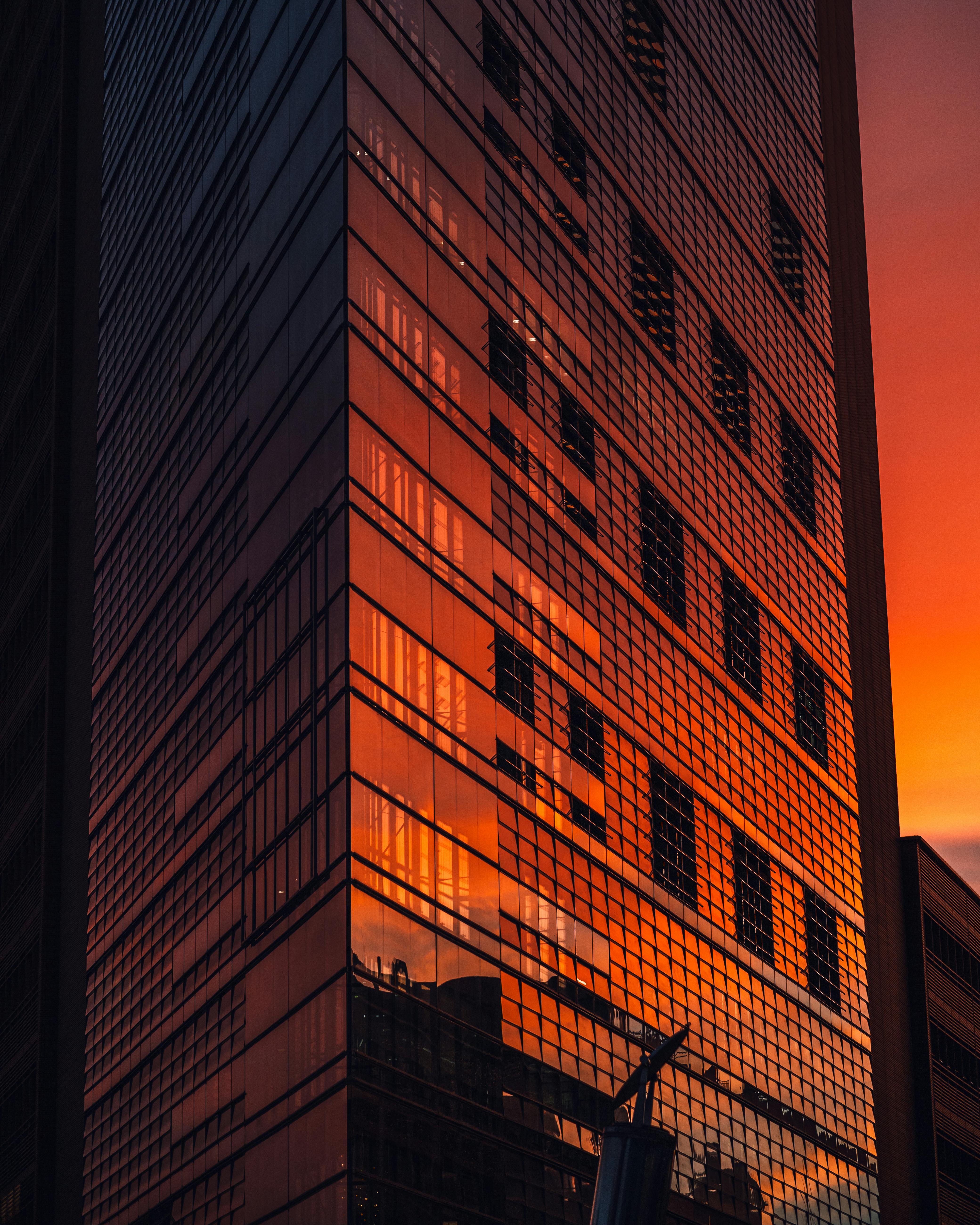 Glass facade of a Berlin skyscraper reflecting a vibrant sunset skyline.