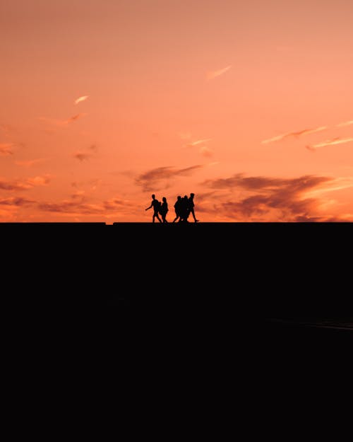 Silhouettes of People Walking at Dusk
