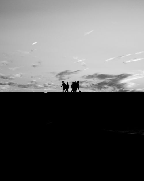 Free Silhouetted group of people walking on a rooftop at dawn, characterized by dramatic black and white contrasts. Stock Photo