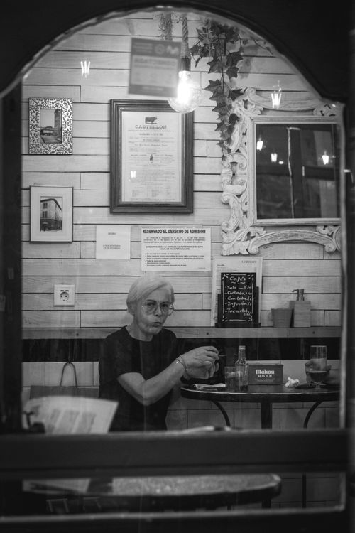 Free Elegant grayscale photo of a woman enjoying coffee at a cafe in Valencia, Spain. Stock Photo