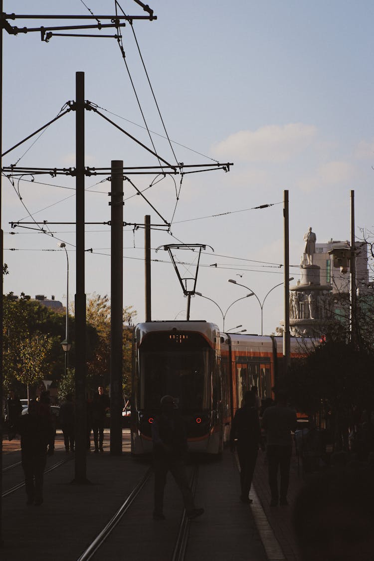 Tram Behind People In Shadow In Town