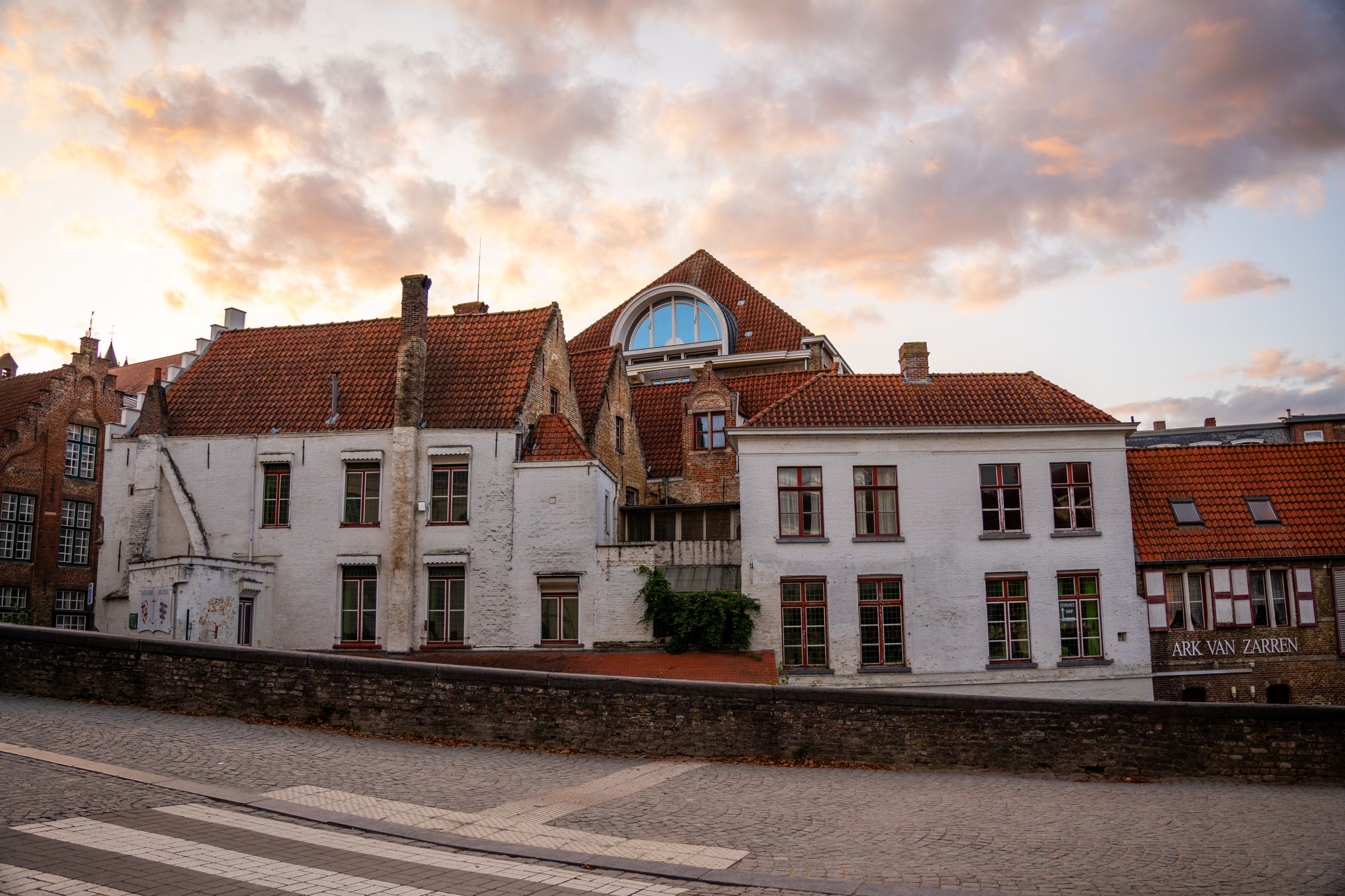 Explore the historic charm of Bruges with this sunset view of traditional buildings in Flanders, Belgium.