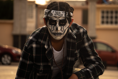 Free Young man with skull face paint and plaid shirt celebrating Day of the Dead outdoors. Stock Photo