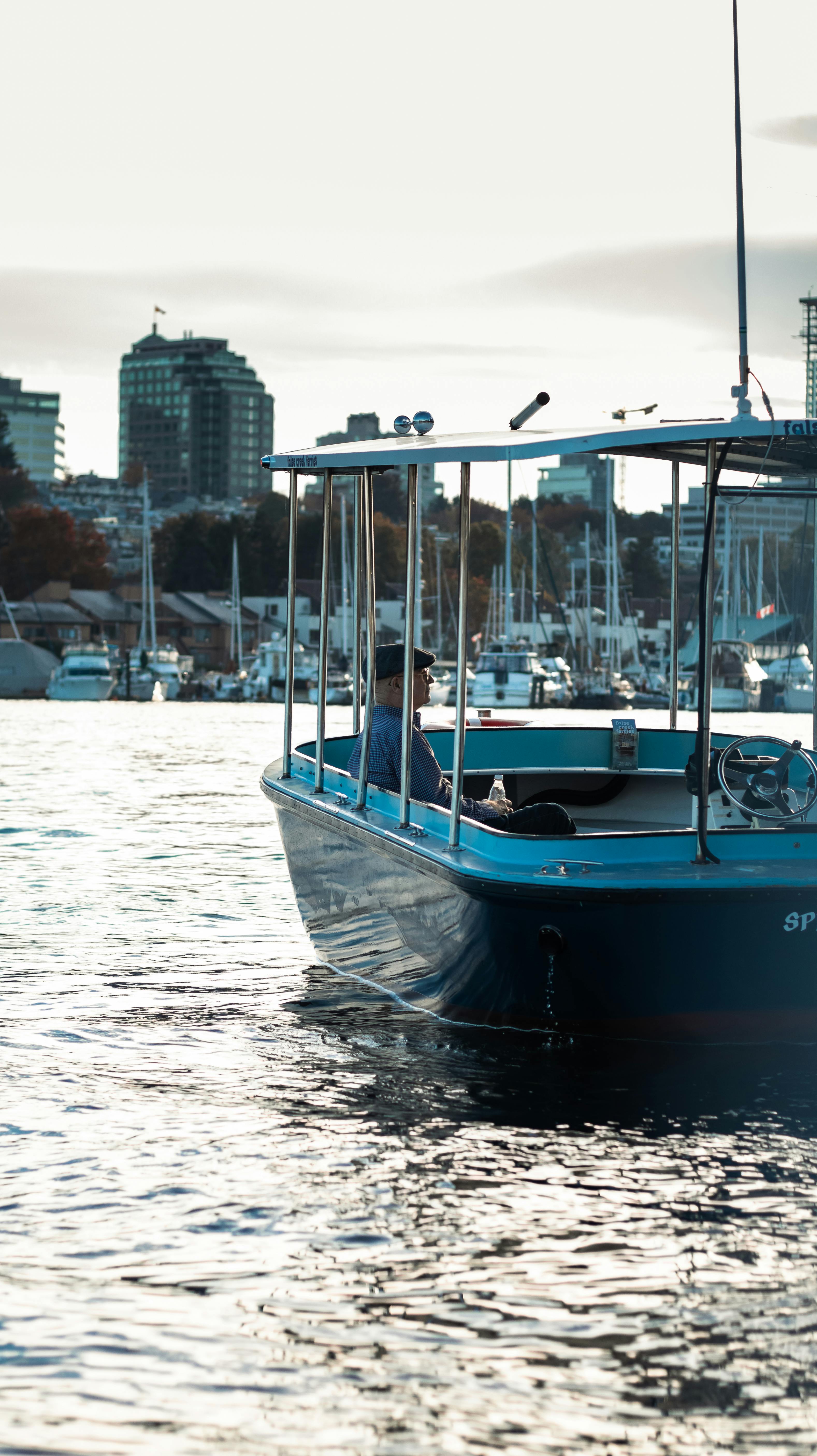A serene view of a tour boat cruising through a city harbor, surrounded by urban buildings.