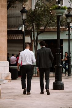 Two men in business attire walking on an urban sidewalk, showcasing city life and street fashion.